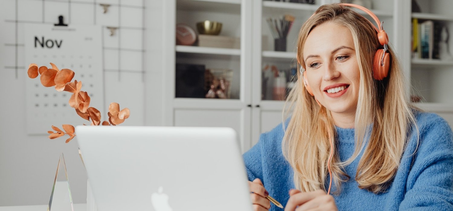 Woman wearing headphones while working at a laptop